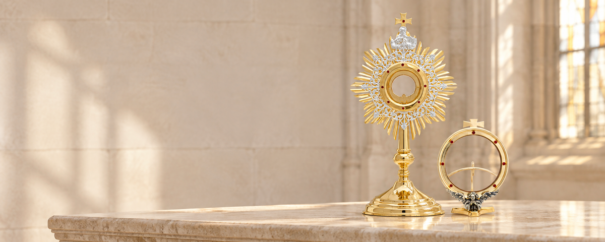 Two monstrances with gold-colored finishes on a pale stone display surface.