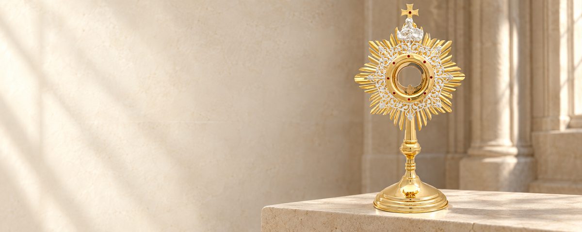 Gold and silver-colored monstrance displayed on a pale stone surface.